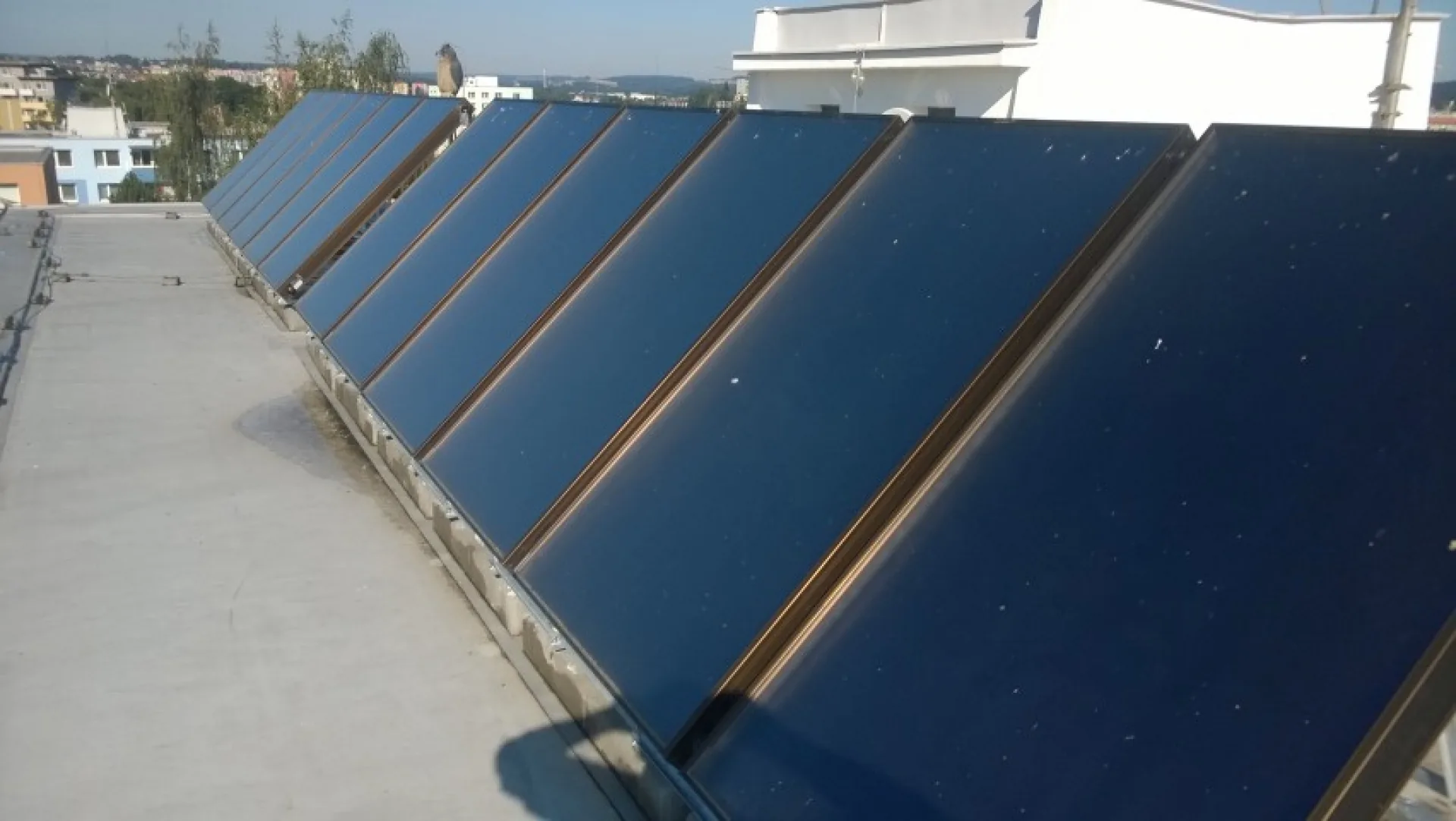 Pole solárních kolektorů na ploché střeše bytového domu