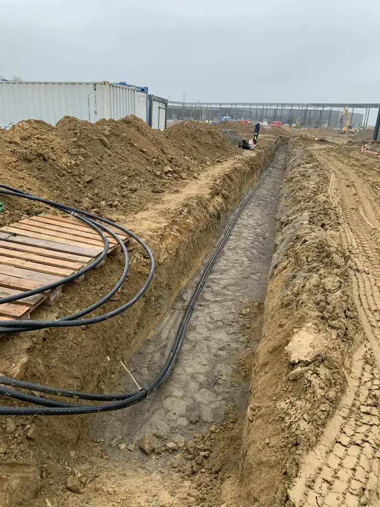 Kabelový výkop s uloženými chráničkami u průmyslové haly