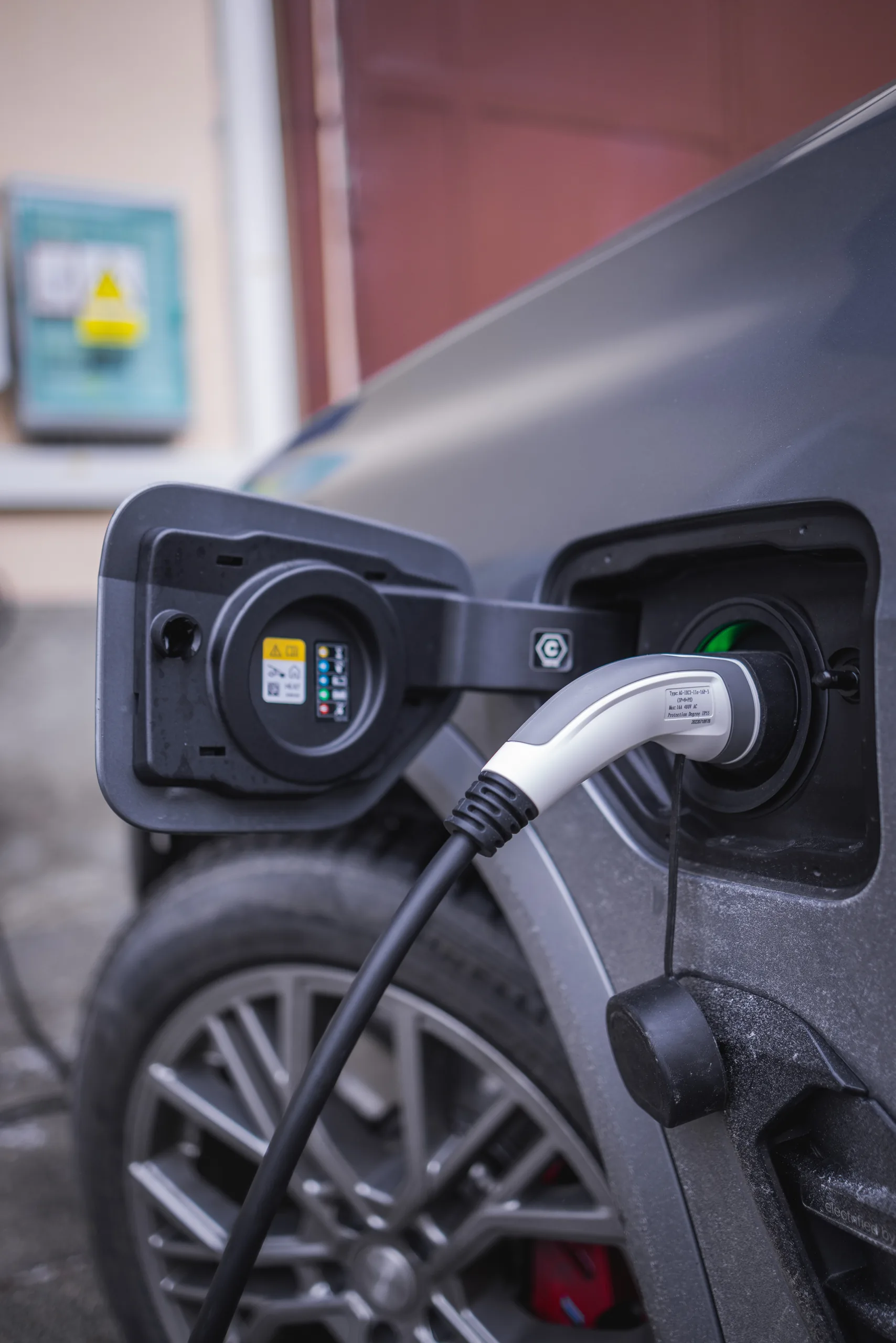 Elektromobil připojený k nabíjecí stanici u budovy