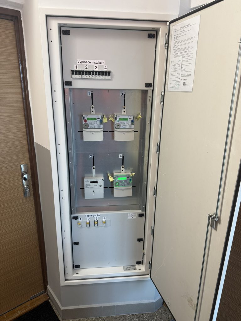 Otevřený elektroměrový rozvaděč s novými jističi a měřením ve společné chodbě