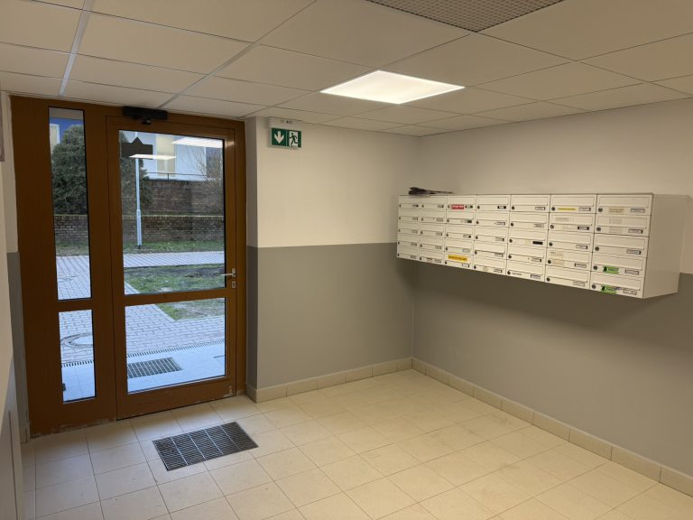 Vstupní hala bytového domu s LED panelem, nouzovým osvětlením a domovními schránkami po rekonstrukci elektroinstalace