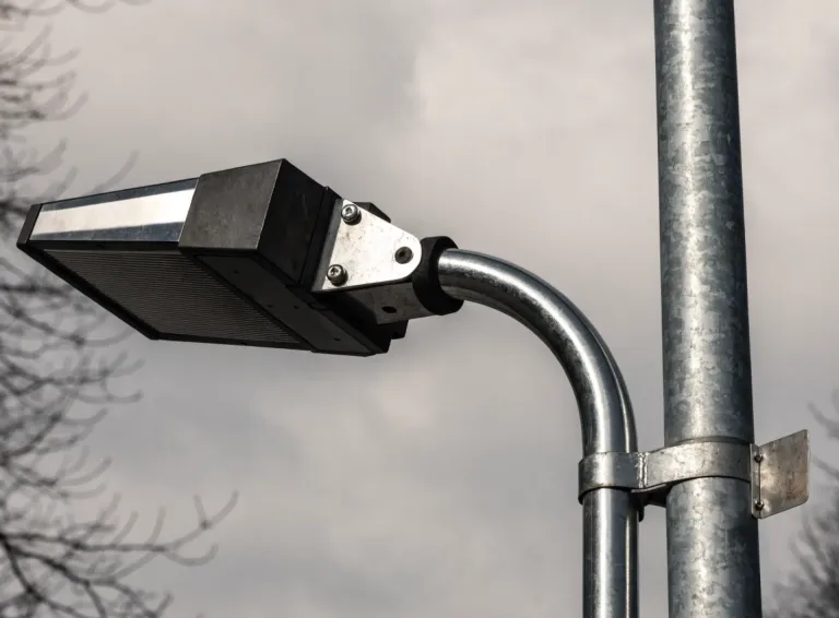 Detail moderního LED svítidla na výložníku pozinkovaného stožáru s identifikačním štítkem