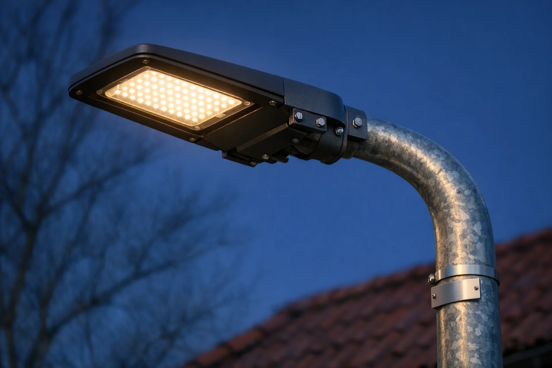 Rozsvícené LED svítidlo na pozinkovaném stožáru veřejného osvětlení za soumraku