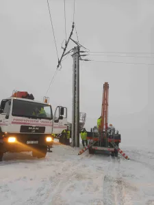 Nákladní vozidlo MAN a pracovní stroj u elektrického sloupu v zimním prostředí při montáži
