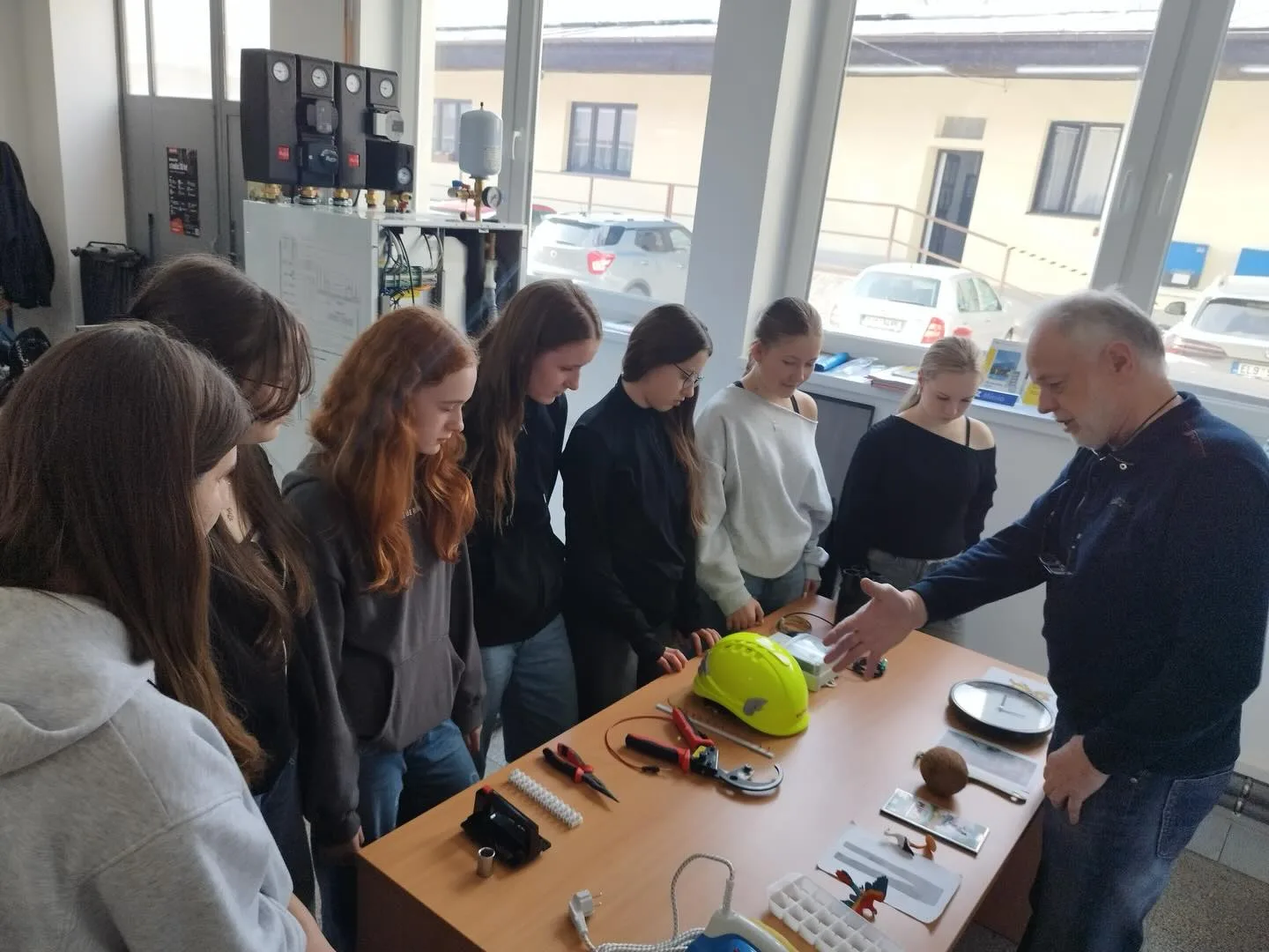 Technik ELPE ukazuje žákům měřicí přístroje a nástroje u pracovního stolu ve školním prostředí