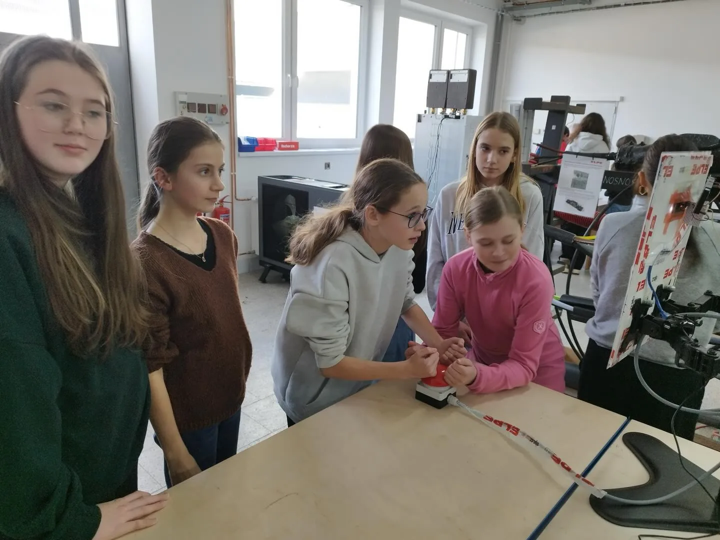 Skupina žákyň sleduje měření na pracovním stole ve výukovém polygonu ELPE