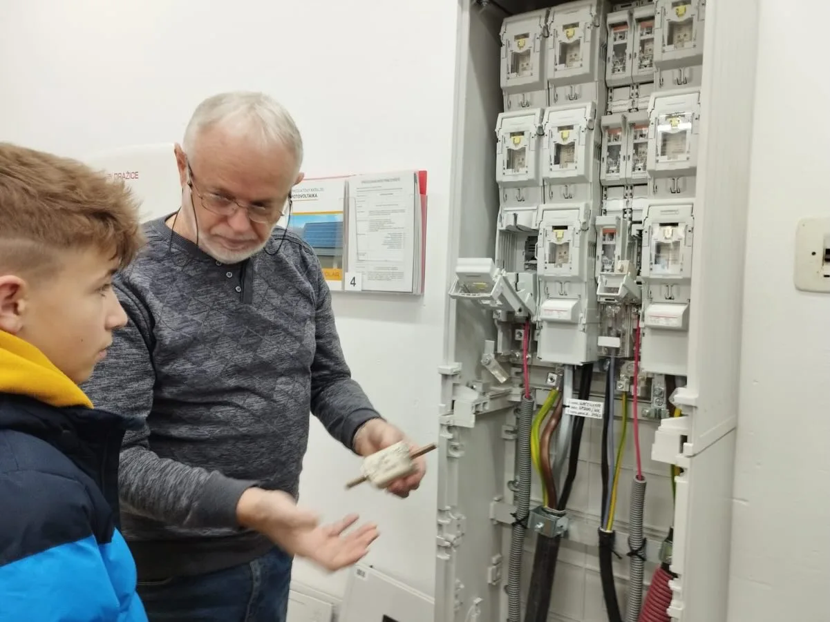 Technik vysvětluje žákovi funkci elektroměrového rozvaděče při školení
