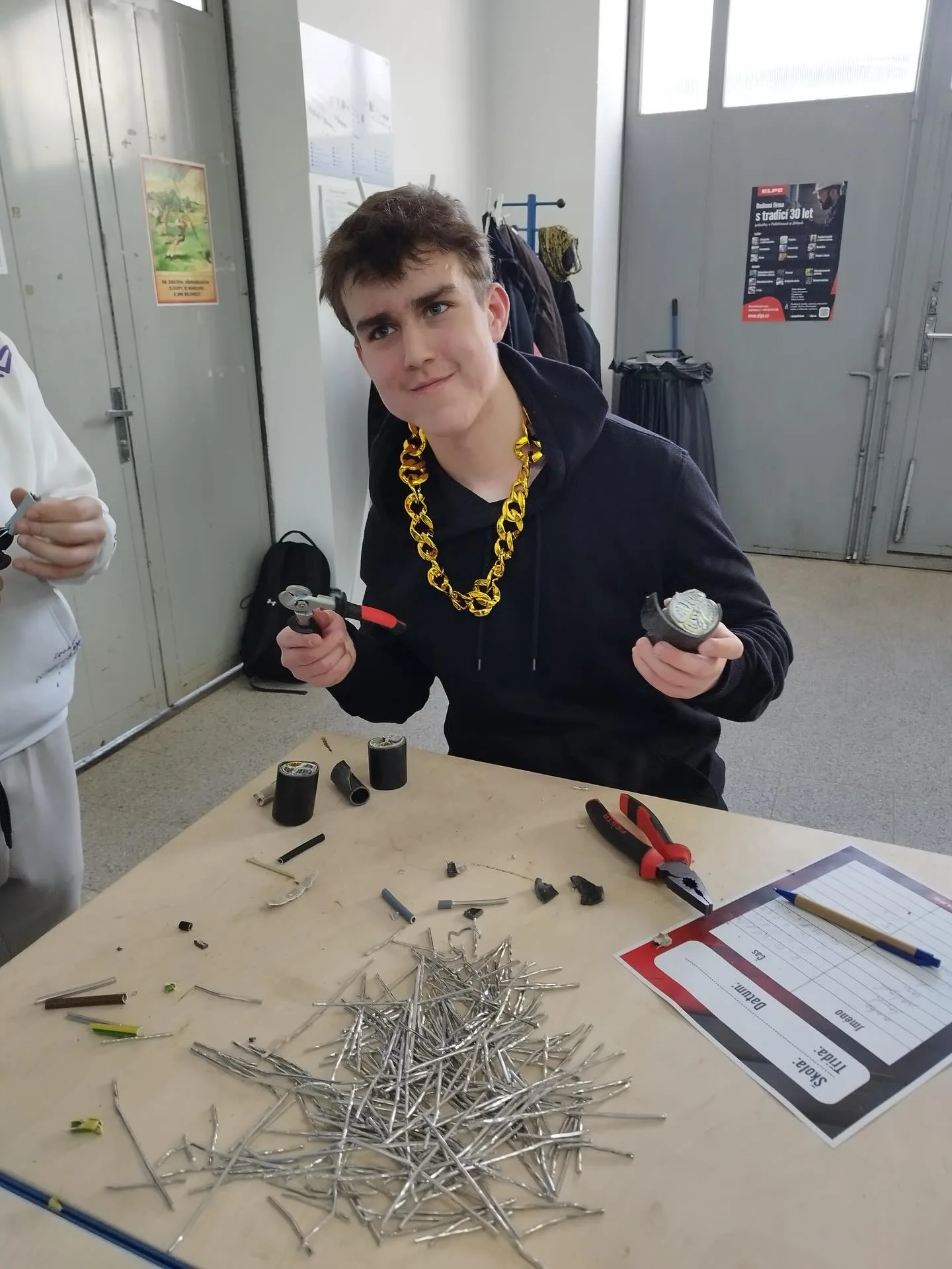 Mladý žák montuje elektrické komponenty na stole během praktického výcviku ve škole